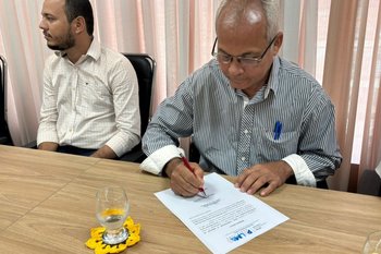 Diretor da Escola Carlos Drummond assinando documento para a construção de um novo prédio escolar.